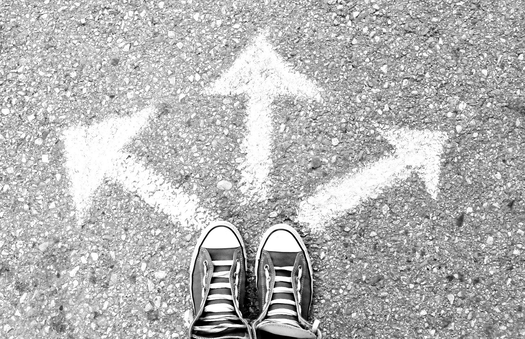 Photo of shoes on the ground with three arrows pointing in different directions.
